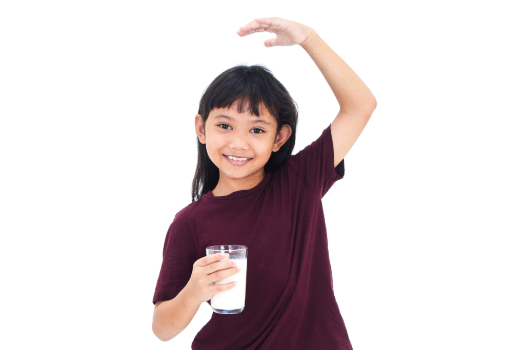 anak tinggi yang sedang tersenyum ke kamera sambil memegang segelas susu