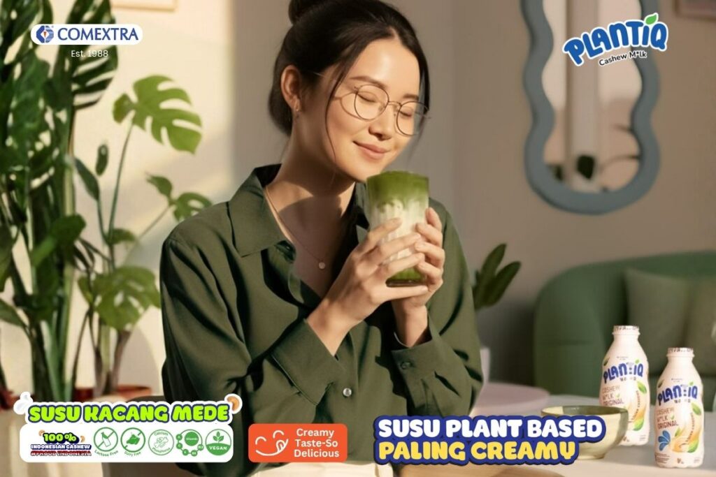 Wanita sedang memegang segelas matcha latte dari PLANTIQ Cashew Milk (Susu Mede).